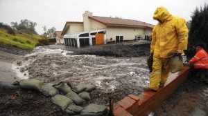 Danny Lopez, left, and Fernando Hacindo work to stem mud and debris flowing down a blocked drain in Camarillo Springs.