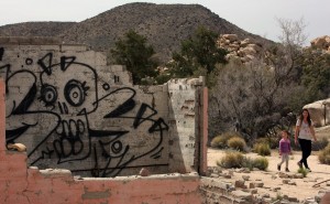 Rebecca Swartz and her daughter Lilly, 5, walk past the remains of pink house in Joshua Tree National Park that has been tagged with graffiti.